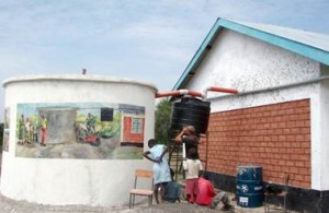 Detta är ett exempel på teknik som används för att förbättra levnadsvillkoren på en skola i Orongo, Kenya. Den mindre svarta tanken säkerställer att det första regnvattnet från taket inte hamnar i den större tanken. Målningen på den stora tanken visar förhållningsregler för tankens användande och underhåll (text var här nämligen inte ett alternativ).
